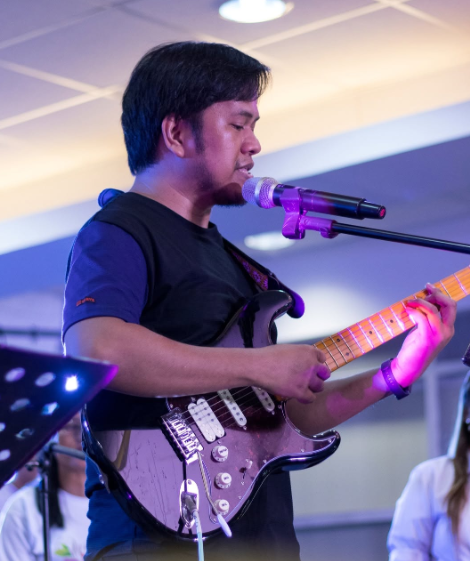 Joshua Ruanes leading worship with guitar